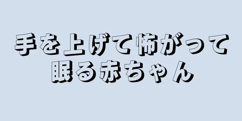 手を上げて怖がって眠る赤ちゃん